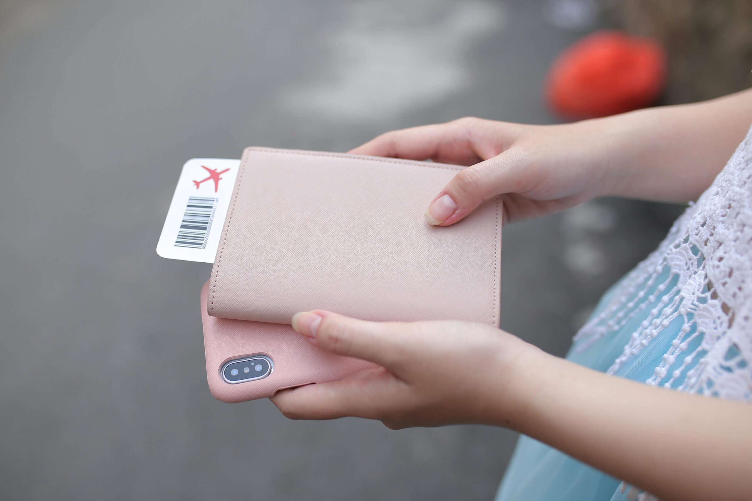 A woman holding a passport with a boarding pass and a smartphone, ready for travel.